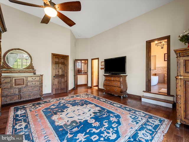 bedroom featuring baseboards, high vaulted ceiling, wood finished floors, and ensuite bathroom