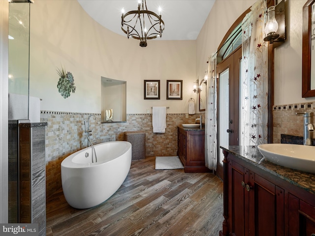 bathroom featuring a sink, tile walls, a freestanding bath, and two vanities