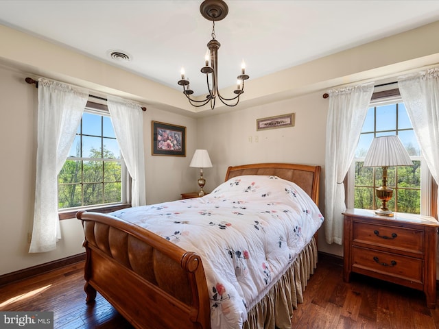 bedroom featuring visible vents, a notable chandelier, multiple windows, and hardwood / wood-style flooring
