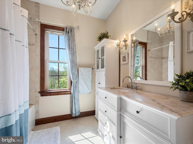 bathroom with a chandelier, a healthy amount of sunlight, tile patterned flooring, and vanity