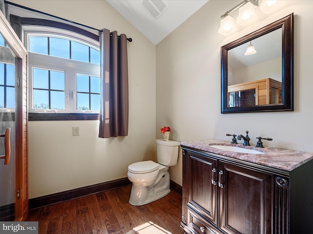 bathroom with visible vents, wood finished floors, toilet, baseboards, and vaulted ceiling