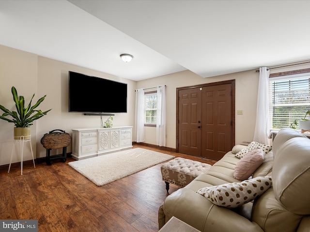 living area with baseboards, dark wood finished floors, and a healthy amount of sunlight