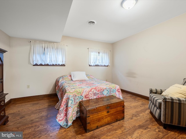 bedroom with visible vents, baseboards, and wood finished floors