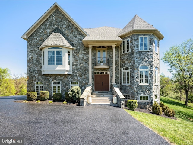 french country style house featuring a balcony and stone siding