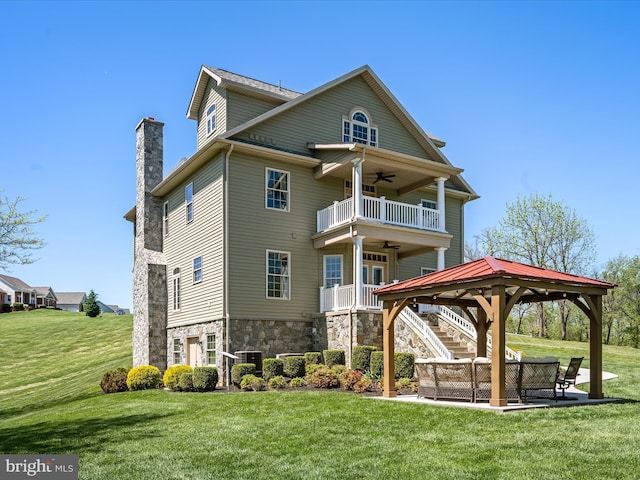 exterior space with a gazebo, stone siding, ceiling fan, a chimney, and a yard