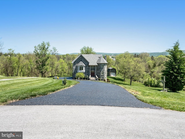 view of front of house featuring stone siding, a front yard, and aphalt driveway