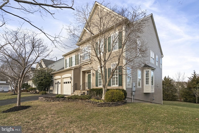 view of front of home featuring an attached garage, aphalt driveway, and a front yard