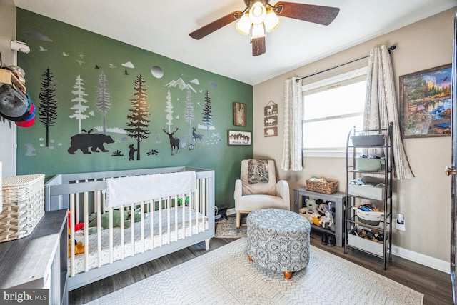 bedroom with hardwood / wood-style floors, ceiling fan, and a crib