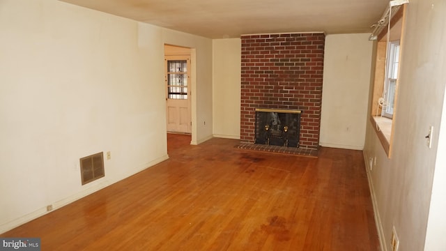 unfurnished living room featuring a fireplace, wood finished floors, visible vents, and baseboards