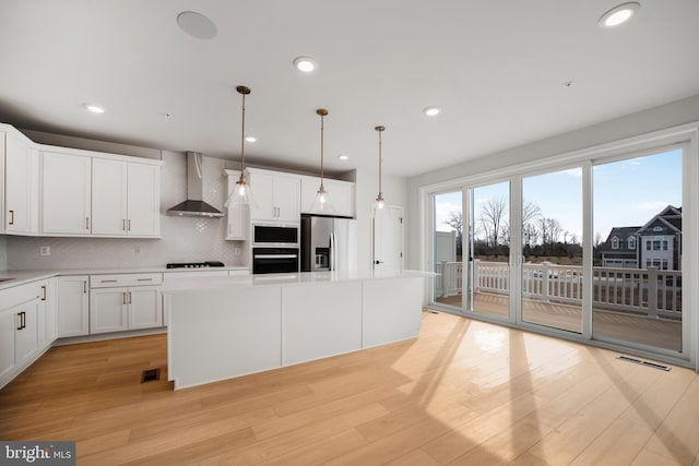 kitchen with a center island, decorative light fixtures, stainless steel fridge with ice dispenser, and wall chimney range hood