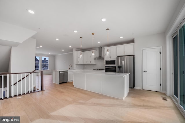 kitchen with wall chimney range hood, pendant lighting, white cabinetry, and black appliances