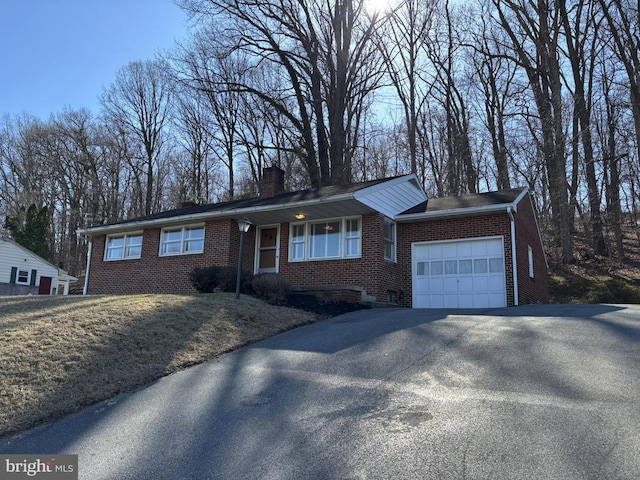 ranch-style home with a garage, brick siding, driveway, and a chimney