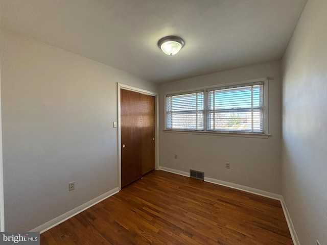 spare room featuring visible vents, wood finished floors, and baseboards