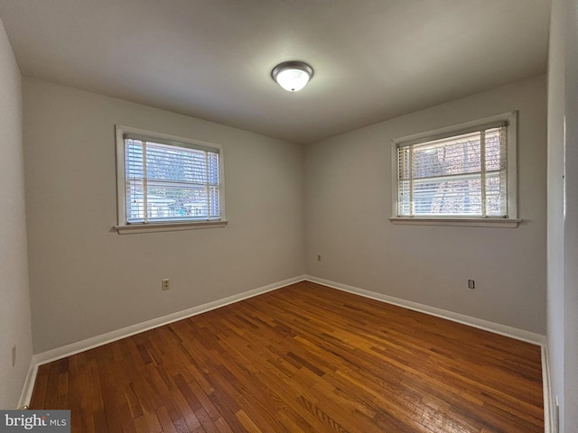 empty room with hardwood / wood-style floors, a healthy amount of sunlight, and baseboards