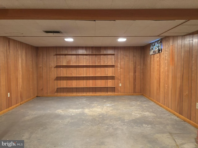 finished below grade area featuring visible vents, wood walls, and baseboards