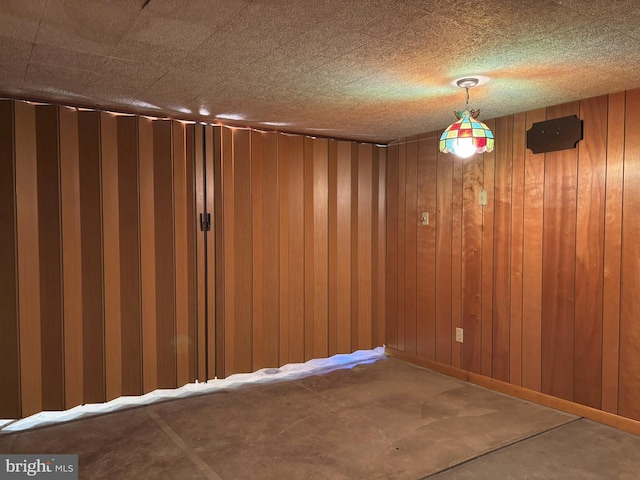 empty room with wood walls and concrete flooring