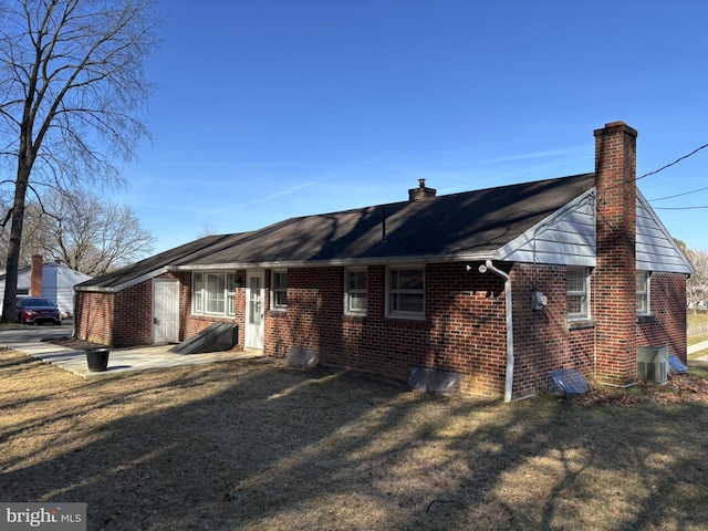 view of front of property featuring brick siding, a chimney, and a front lawn