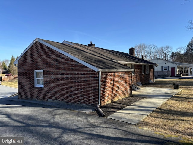 view of side of home with brick siding and a chimney