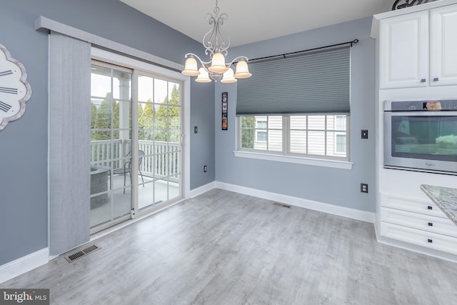 interior space featuring light wood finished floors, baseboards, visible vents, and a chandelier