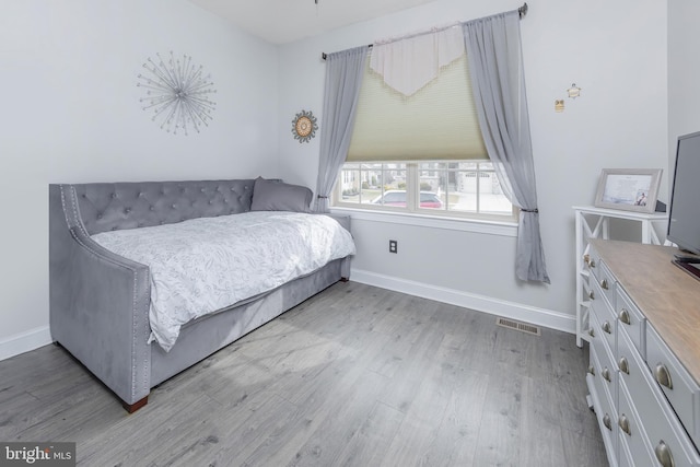 bedroom featuring baseboards, visible vents, and light wood finished floors