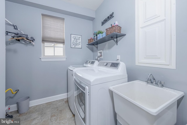 laundry room featuring laundry area, washing machine and clothes dryer, a sink, and baseboards