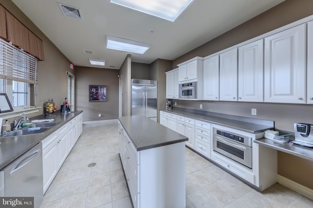 kitchen with dark countertops, visible vents, appliances with stainless steel finishes, white cabinets, and a sink