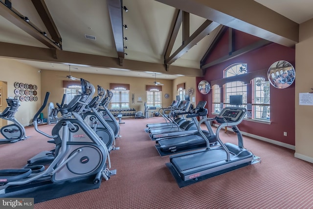 exercise room featuring high vaulted ceiling, visible vents, and baseboards