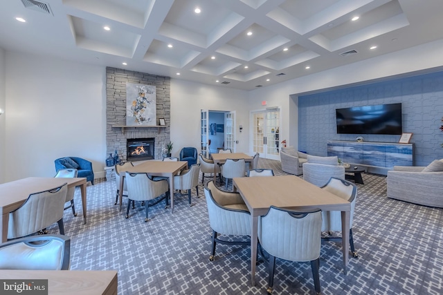 dining room with visible vents, coffered ceiling, dark carpet, and a stone fireplace