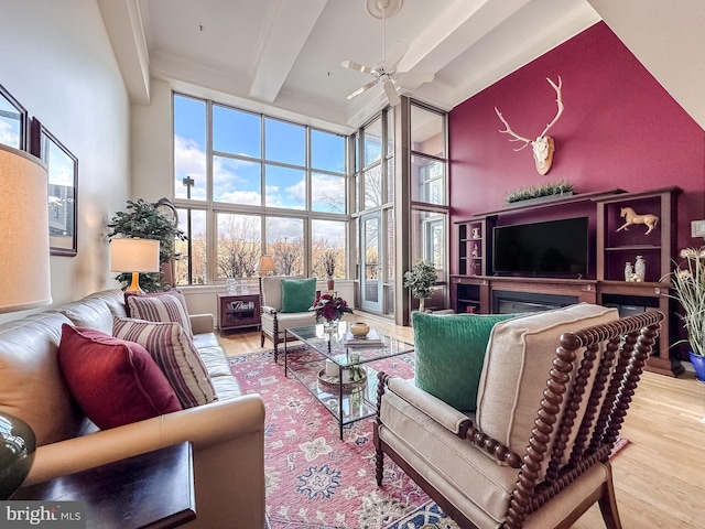 living room with beam ceiling, ceiling fan, a towering ceiling, and hardwood / wood-style floors