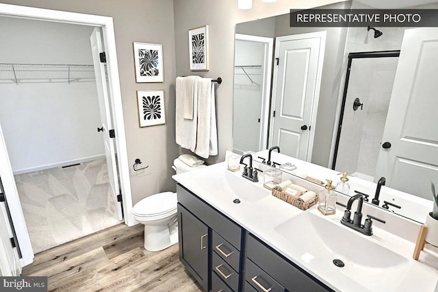 bathroom with toilet, wood-type flooring, an enclosed shower, and vanity