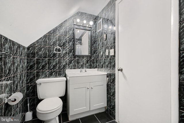 bathroom with toilet, tile patterned floors, tile walls, and vanity