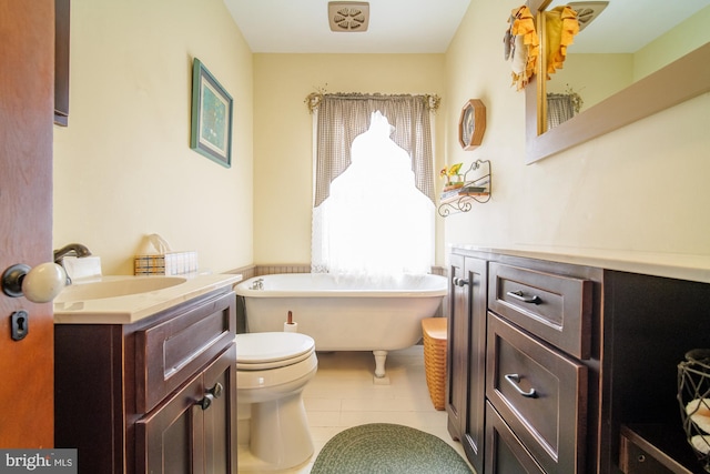 bathroom with a freestanding bath, vanity, toilet, and tile patterned floors