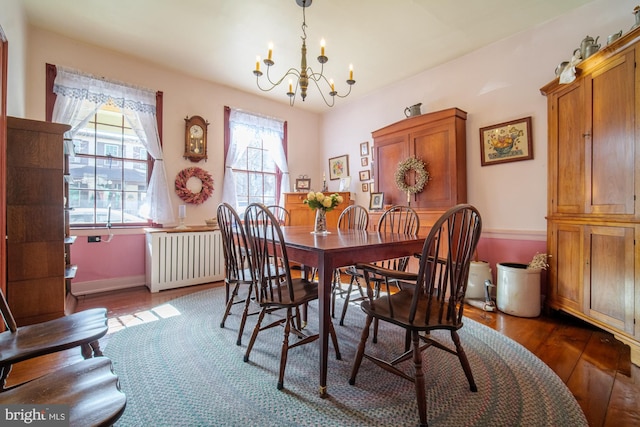 dining room featuring dark wood-type flooring, radiator, baseboards, and an inviting chandelier