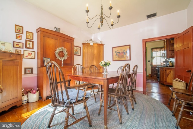 dining area featuring visible vents, a chandelier, and dark wood-style flooring