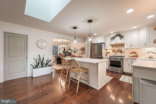 kitchen featuring premium appliances, hanging light fixtures, white cabinetry, and a center island