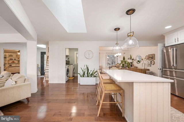 kitchen featuring white cabinetry, dark wood-type flooring, a kitchen bar, high end fridge, and pendant lighting