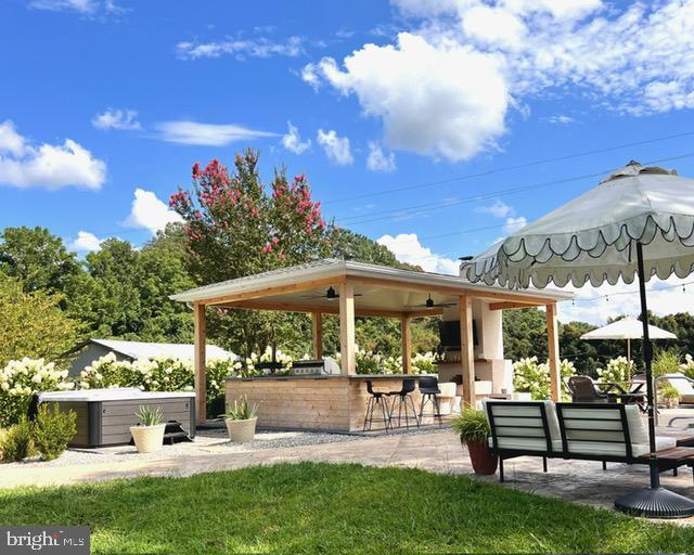 view of property's community with an outdoor bar, a patio area, and a hot tub