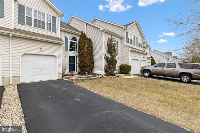 view of front facade featuring a shingled roof, a front yard, driveway, and an attached garage