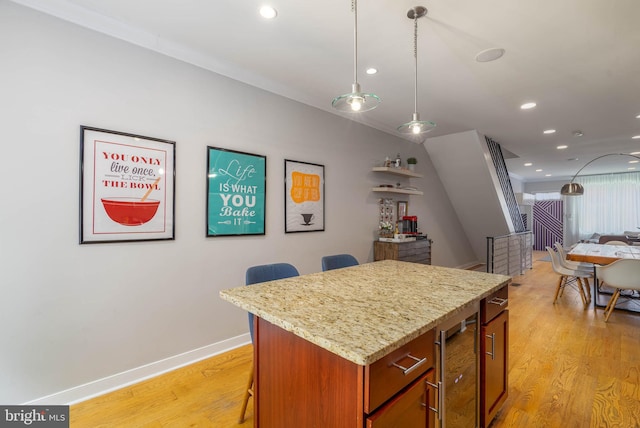 kitchen with light hardwood / wood-style flooring, a kitchen island, a breakfast bar area, and decorative light fixtures