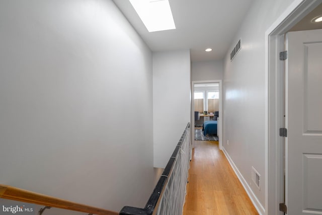 hallway with light hardwood / wood-style floors and a skylight