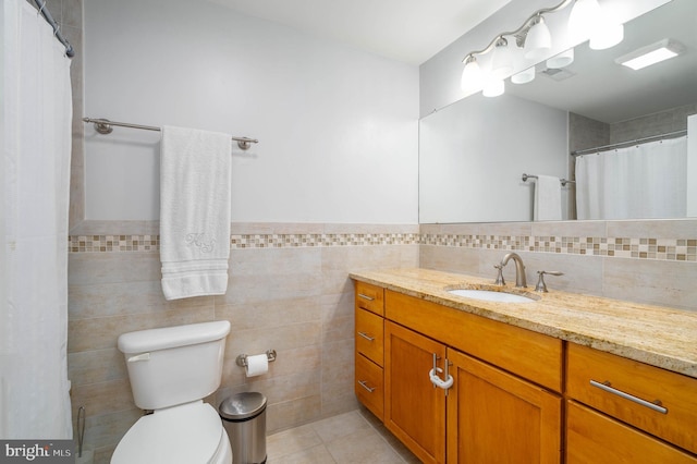 bathroom with toilet, tile walls, tile patterned flooring, and vanity