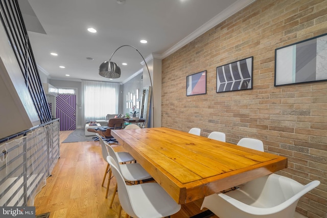 dining room with light hardwood / wood-style floors, crown molding, and brick wall