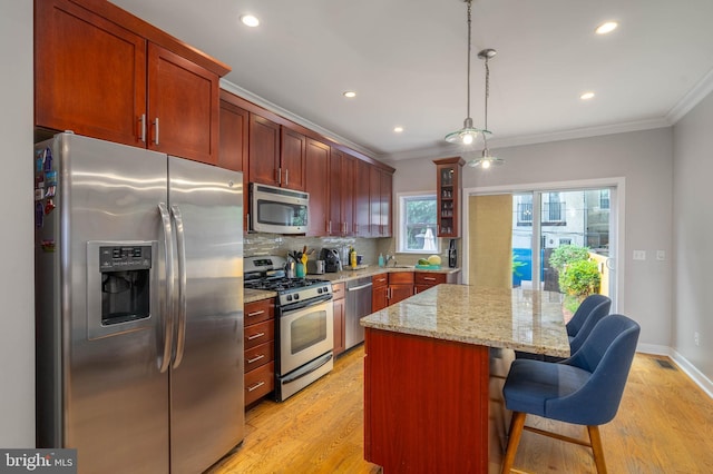 kitchen with appliances with stainless steel finishes, a kitchen island, crown molding, and a breakfast bar area