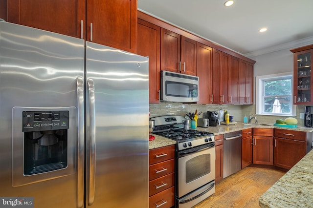 kitchen with stainless steel appliances, crown molding, light stone countertops, and backsplash