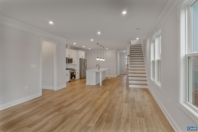 unfurnished living room featuring light wood-type flooring, sink, and ornamental molding