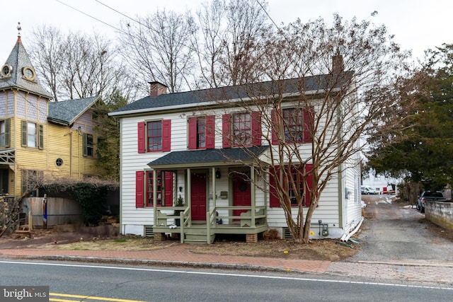 view of front facade featuring covered porch, roof with shingles, and a chimney