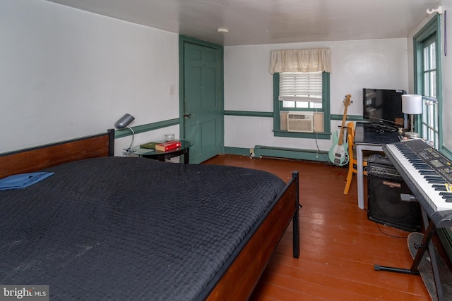 bedroom featuring baseboard heating, multiple windows, cooling unit, and wood finished floors