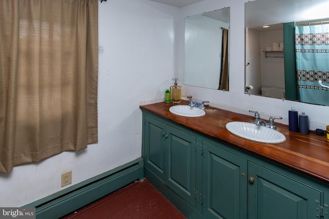 full bath with a sink, double vanity, toilet, and a baseboard radiator