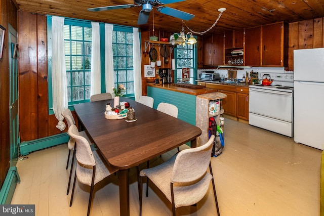 dining space featuring light wood-style flooring, wood ceiling, wood walls, and baseboard heating