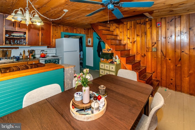 dining area with stairs, wood ceiling, wood-type flooring, wood walls, and ceiling fan with notable chandelier